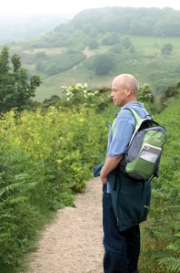 John carrying rucksack, path goes up and down ahead. Ruth's coastal walk.