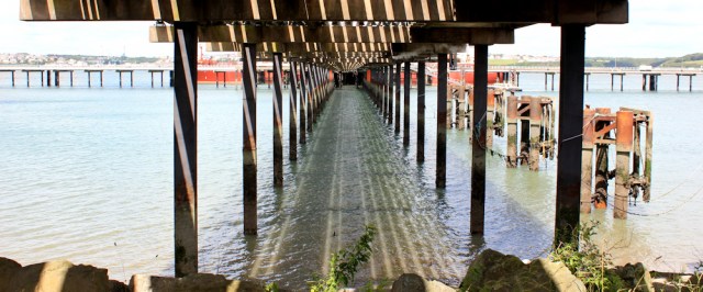  under the jetty of the oil refinery, Ruth hiking towards Pembroke