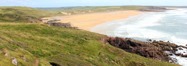  looking back Freshwater West, Ruth hiking in Wales